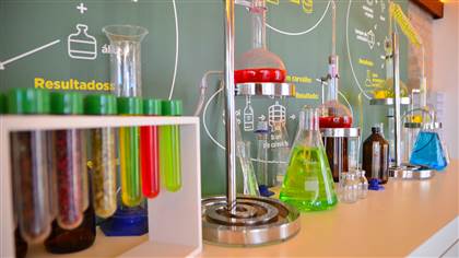 Foto de vários frascos de vidro, com diferentes formatos, preenchidos com líquidos coloridos.
